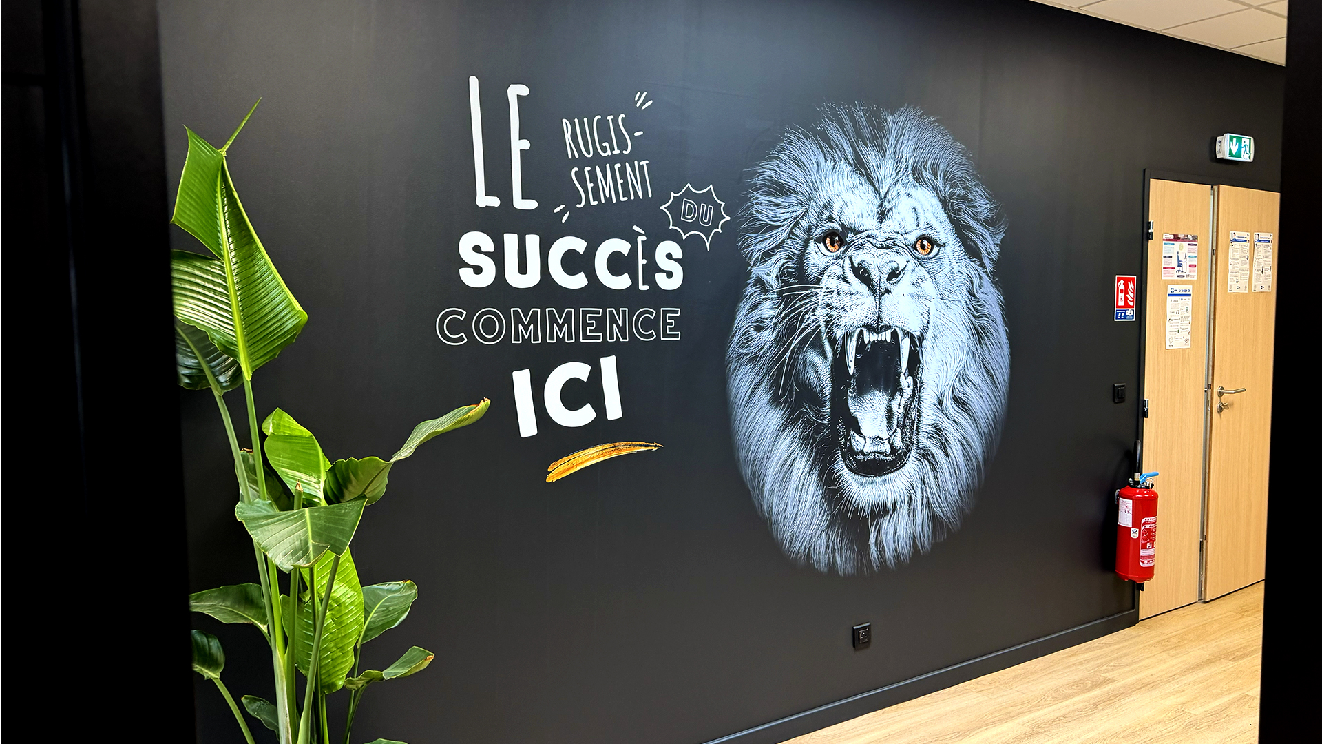Photo d’un lion aux yeux dorés imprimé sur un mur sombre, accompagné du texte « Le rugissement du succès commence ici »